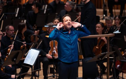 A presenter in front of an orchestra