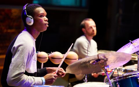 A young person playing drum kit