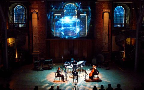 Musicians performing in front of projected graphic